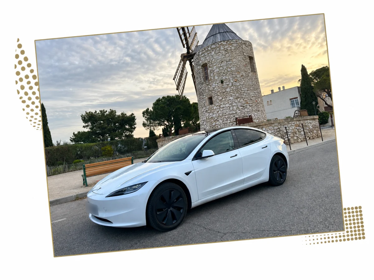 Tesla Model 3 blanche devant un moulin en pierre