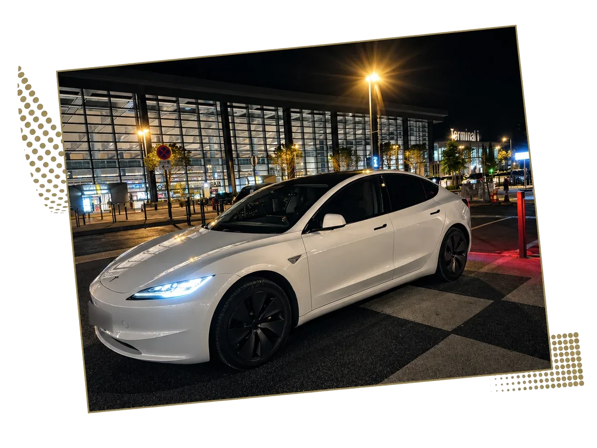 White Tesla Model 3 in front of the glass facade of a night terminal